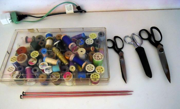 Misc sewing threads with scissors and knitting needles.