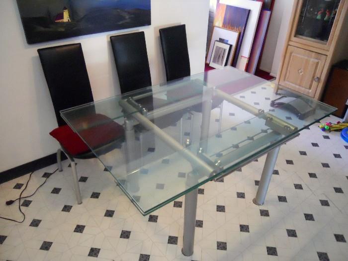 Modern glass table with three black chairs.