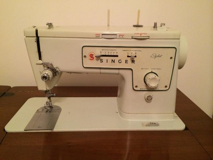 Vintage electric singer sewing machine in cabinet.