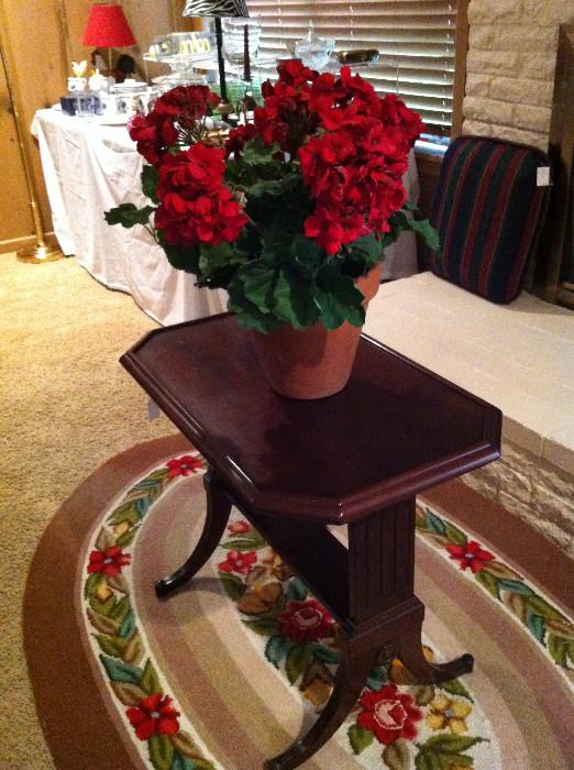 Small coffee table; geranium arrangement; small oval rug