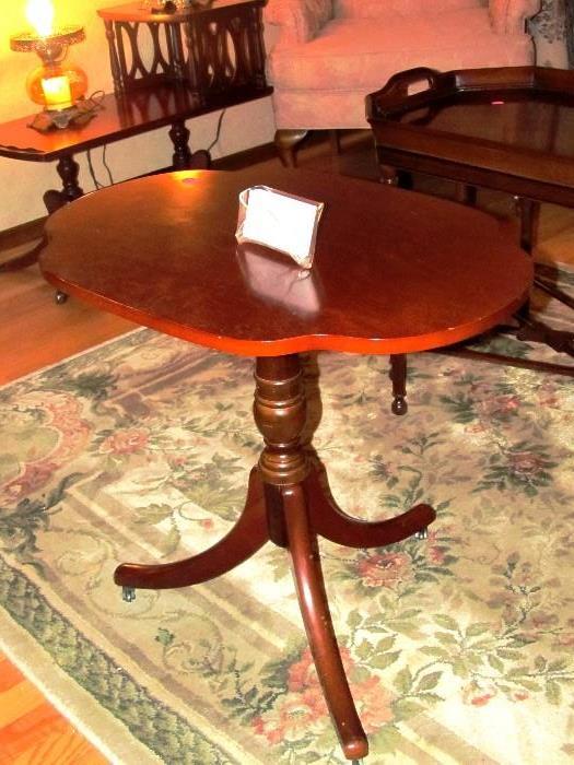 Vintage Scalloped Table with three legs, and a rich finish; Also shown is a room sized European Style Rug with floral accents. 