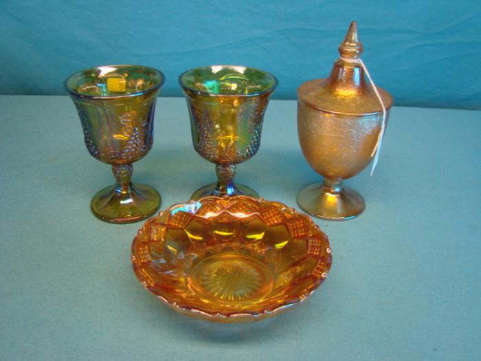Four pieces of beautiful carnival glass; Two very nice grape goblets, one lidded goblet, and one candy bowl with underside raised pattern and a deep marigold tone. All pieces appear to be depression-era, and are all in great condition
