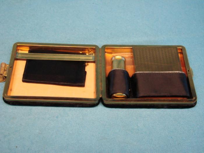 Antique women's portable vanity kit; Includes compact, lipstick holder, a small comb, a wallet side with a cigarette holder, and a small coin purse. Black felt with gold trim. Doesn't appear to have a maker's mark. Please see pictures.