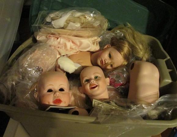 Bins filled with porcelain doll heads, body parts, hair, eyes and clothing along with firing molds for manufacturing even more