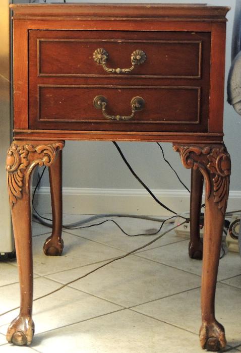 One of a pair of leather top end tables with foliate carved knees and ball and claw feet.