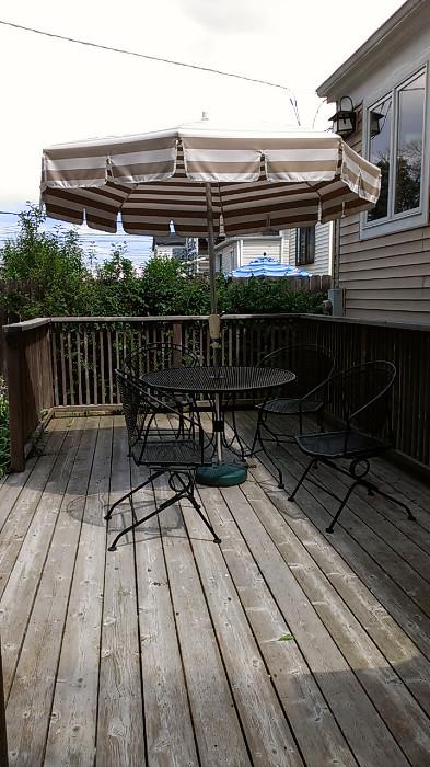 Patio table with four chairs, umbrella, and base.