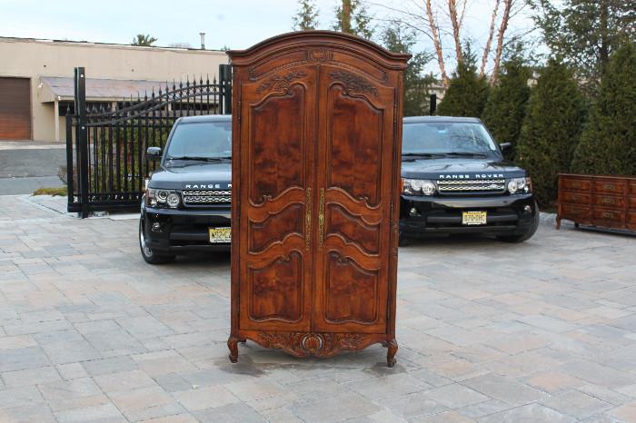 ITEM # 1030Before us is a stunning "Country French" style two door Armoire handcrafted by Henredon.  From their "Premier Villandry Collection", this armoire features stylish carved details, rich finishes and a wonderful fitted interior. The intricately picked hardwood and veneer that was implemented into this piece includes walnut and other choice materials. With both opulence and functionality captured within the design, the time, effort and thought which went into the construction of this piece shows the quality of the company's craftsmen. The top molding, corner chests, bottom trim and darkened grain door inlays sets this piece apart from others. The removable dividers on each shelf and roomy bottom drawers, create for a practical yet stylish armoire. This piece originally sold for: $2,000.00. This piece is part of a bedroom set that we have available for sale which includes a "Dresser & Mirror". If you are interested in this matching item please view our additional inventory. 