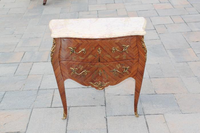 ITEM # 1068

Offered here is an exquisite “antique-era” miniature French commode embellished with an intricate pink marble top. The term “commode” is derived from early French dialect regarding something that is convenient/agreeable referring to a furniture piece containing drawers. This Louis XVI styled miniature commode would be a wonderful focal point to any living space. This piece was skillfully created using the finest hardwoods and inlays and truly represents the expertise and passion of the craftsman. Multiple exotic hardwoods were used in the creation of this piece. Rare hand formed metals were implemented in the design including the handles, corner crests, lock sets and base trim in order to further add richness to the overall aesthetic of the piece. It is important to note that when closely examining all sides of this one of a kind miniature commode, the original craftsman added a zebra wood design which flows around the entire piece, irregardless of the fact that some side 