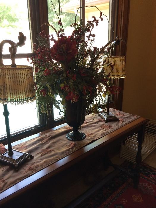 Sofa table; beautiful floral arrangement; antique lamps