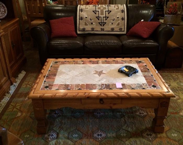 Dark brown leather sofa, Navajo rug, and natural pine coffee table with inlaid tile top.
