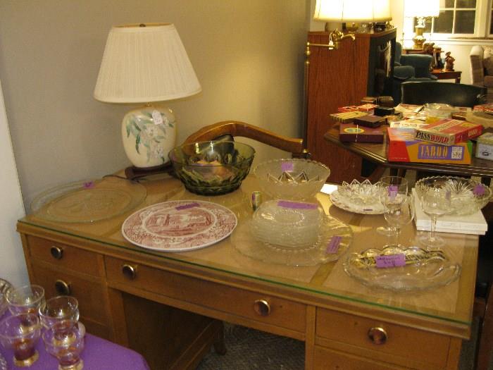 Nice variety of dishes and lamp on a old antique desk. with glass top.