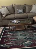     Long sofa; rattan/glass coffee table; "fish" rug (1 of 3 identical rugs)