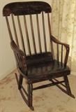 The spindle back ‘Boston Rocker’ Rocking Chair having the traditional rolling seat, curved arms, large crested top trail, six spindles with open arms and turned legs -stretcher on sleigh rockers, third quarter of nineteenth century America.