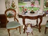 Balloon-back parlor chair, Turtle-top Mahogany marble top parlor table, European rose color font oil lamp, doll in doll-size chair.  In bay window are the Bradley & Hubbard brass bracket lamps.  