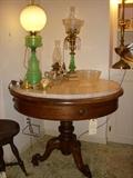 Beautiful marble top walnut table displaying green opaline GWTW lamp, and the Solar kerosene lamp with prisms, as well as other lamps