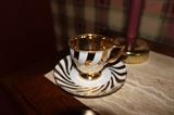 gold and white cup and saucer