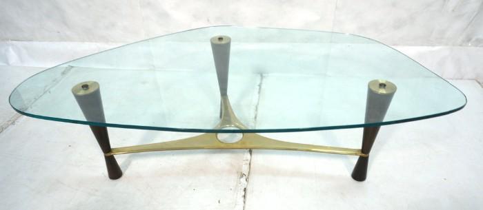 Lot 44  -  DUNBAR Glass Top Walnut & Brass Coffee Table. Edward Wormley designed. Model 5309. Shaped 1/2" glass on three corseted walnut legs. Brass stretcher and caps. -- Dimensions:  H: 16.5 inches: W: 57.5 inches: D: 31.25 inches --- 