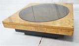 Lot 179  -  Baughman style Coffee Table. Burled wood with brass inlay. Smoked glass center. Stepped back base. Not marked.-- Dimensions:  H: 15.25 inches: W: 40 inches: D: 40 inches --- 