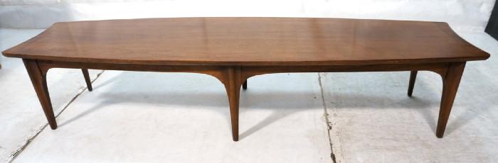Lot 205  -  American Modern Walnut Surfboard Coffee Table. Six Shaped legs. Contrasting edge trim. Arched skirt-- Dimensions:  H: 14 inches: W: 70 inches: D: 20 inches --- 