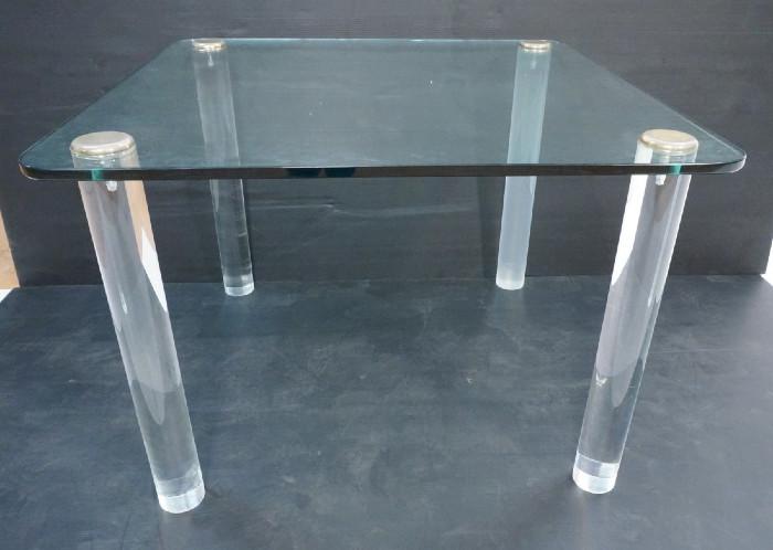 Lot 314  -  Springer Style Lucite and Glass Dining Table.  3/4" thick glass and 3.5" thick Acrylic legs.  Metal caps.-- Dimensions:  H: 29.25 inches: W: 42 inches: D: 42 inches --- 