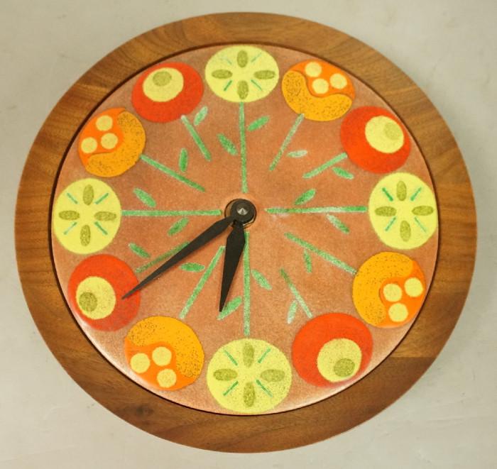 Lot 386  -  Enamel Face Modernist Teak Wall Clock. Enamel floral design in teak frame. Battery operated.-- Dimensions:  H: 9.5 inches: W: 9.5 inches: D: 1.75 inches --- 