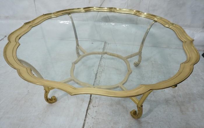 Lot 739  -  Brass & Glass Decorator Cocktail Table. Scalloped Brass edge glass table top. Fancy feather form feet.-- Dimensions:  H: 19.25 inches: W: 41.75 inches: D: 41.75 inches --- 