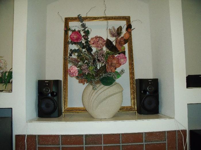 Unique 3 dimensional still life.  Vase with flowers in front of a free standing frame.  Speakers part of Sony surround sound system.