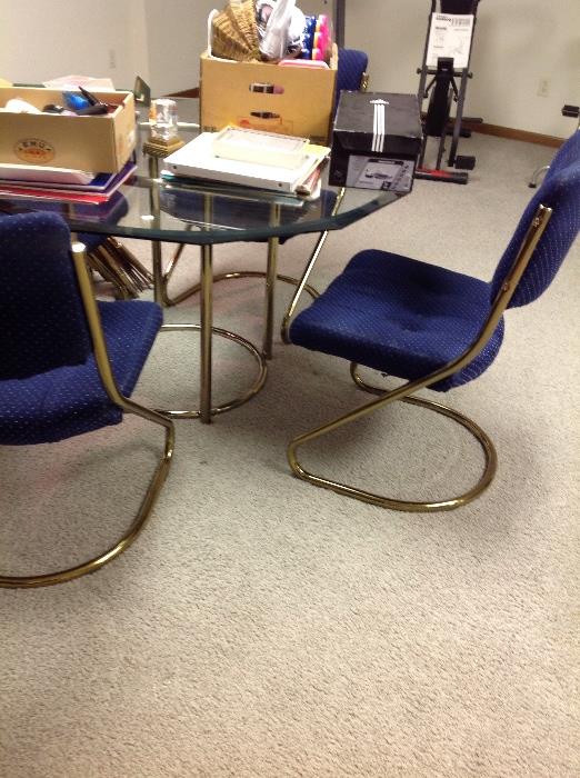 Groovy retro glass and gold table, chairs have blue upholstery