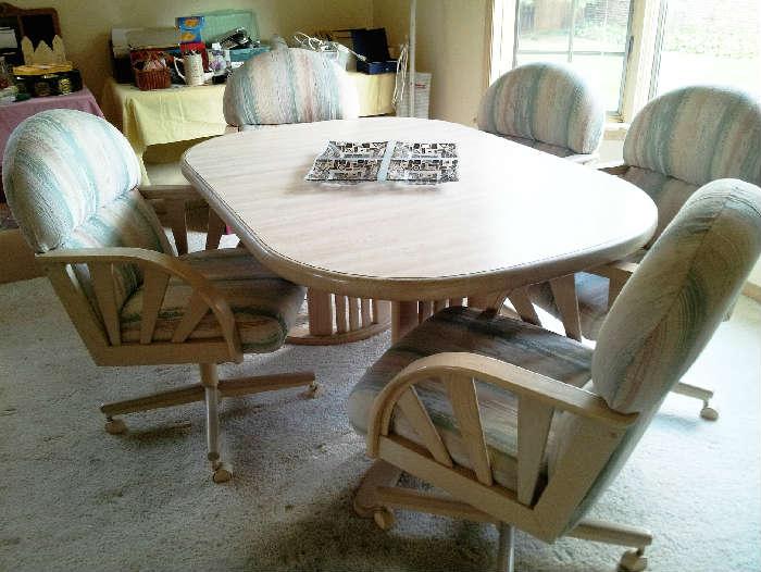 light color wood kitchen table with caster bottom chairs. 