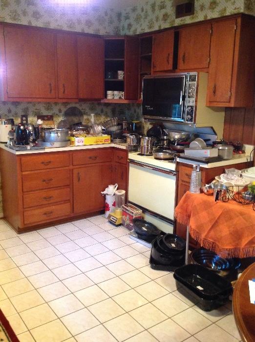 Kitchen packed with dishes, pots, pans, appliances.