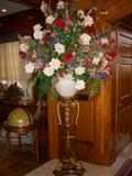 One of a pair of pedestals supporting oversize silk floral arrangements.