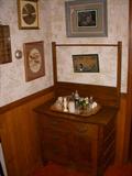 Oak commode with towel bar displaying collection of salt & pepper shakers.