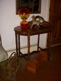 Ca. 1925 table, with newer oil lamp, horse figurine and electric mantle clock (not working).  On floor to left of table is a 1920's cast iron magazine rack