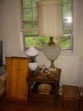 Table, Lamps, Knickknacks.  To left of table, standing on end, is a small cradle