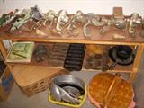 Assorted collectible primitive kitchen items including food grinders, cherry pitters, and cast iron muffin pans, etc.