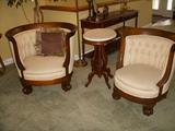 Curved club chairs with carved mahogany frames.  They match the sofa.  Between the chairs is an oval walnut marble top stand.