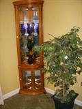 Oak curved glass lighted curio holding 3 blown glass water pitchers (cobalt blue, emerald green & amethyst)