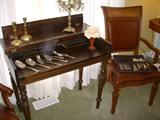 1920's Spinet desk displaying Victorian era silverplate serving utensils.  To the right of the desk is one of the Stanley dining chairs....on its seat is a set of silverplate flatware