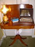 Mahogany veneer flip-top game table holding an amber glass lamp and stainless flatware.