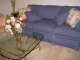 Brass & glass coffee table and blue three-cushion sofa