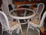 A wicker and glass top table with 4 matching chairs