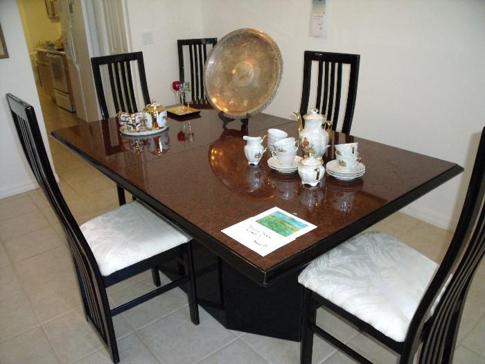 Black lacquer and mottled wood finish dining table with 1 leaf. Black lacquer chairs (6) with upholstered seats