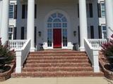 The front porch of the home shows the pair of heavy cast iron urns/bases that are for sale.  