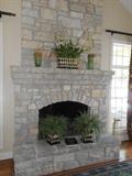 Kitchen/Hearth Room:  The stone fireplace and mantel host metal containers of greenery and two green vases.  To the right of the hearth is a brass fireplace tool set which has a golf theme.