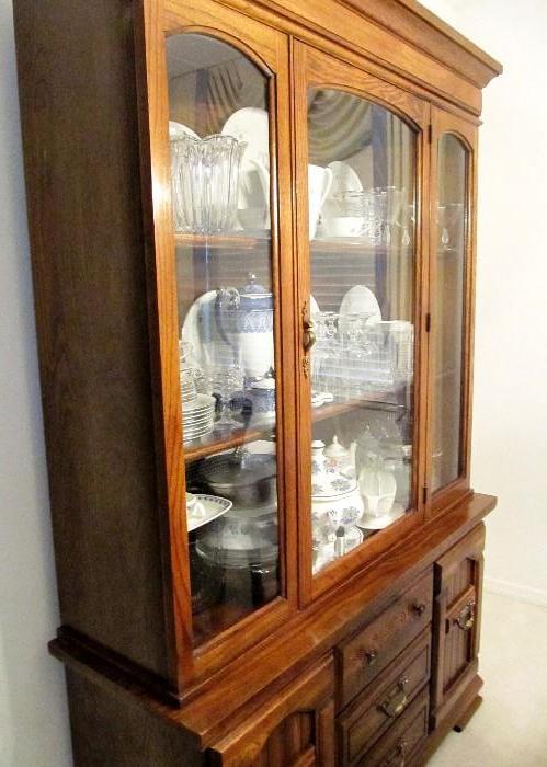 Beautiful Vintage Country Style Triple China Cabinet with wood & Glass Door & Lighted Shelved Storage / Display.  Cabinet has side bottom cabinets and center bottom drawer storage.  Cabinet has rich finish with scrolled decor.  China Cabinet it part of One of Six High Back Dining Chairs with Cane backs and decorative trim, plus neutral upholstered seats.  (I Arm Chair, 5 Side Chairs).  Dining Chairs are part of Beautiful Country Style Dining Set...Includes Country Style Rectangular Shape Table with extra leaf, beautiful Rich Finish; 6 Matching High Back Dining Chairs with Cane Backs, and Lovely Decorative Trim, (5 Side Dining Chairs, 1 Arm Chair), all chairs have neutral upholstered seats; and this Matching Country Style China Cabinet with Wood and Glass Door and lighted shelved storage / display.  Cabinet has side bottom cabinets and center bottom drawer storage with brass pulls .  Dining chairs, dining table are pictured elsewhere in this collection.