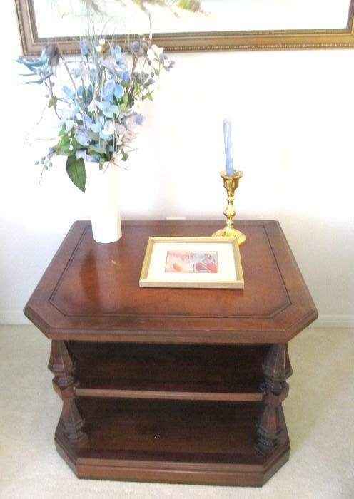 Vintage Traditional Style End Table with front angle cut top, nicely carved spindled shelf supports, and bookcase storage.  End Table is matching to Vintage Traditional Style Coffee Table ,   Vintage Traditional Style Sofa / Foyer Table, and other Vintage Traditional Style End Tables  which are  pictured elsewhere in this collection.  Artworks, brass candle holder, and vase with floral arrangement are also available.