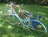 Blue vintage Schwinn Suburban women's bike with basket, light and baby seat. Red vintage Schwinn men's bike.