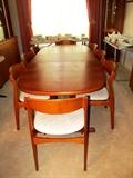 Beautiful Vintage Scan DesignTeak Wood Dining Set... Large oval shaped Teak Dining Table... shown with extra leaf, rich finish, pedestal style base, and unique hideaway for extra leaf; 8 matching teak wood chairs with neutral sculpted upholstery.
