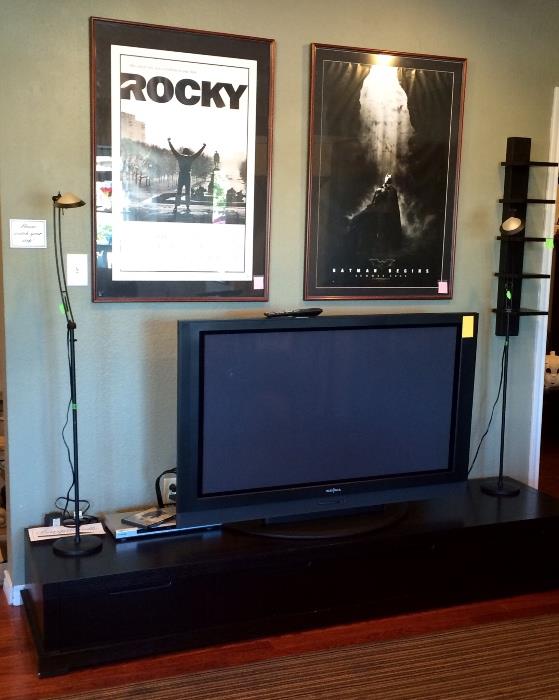 Large flat screen TV, black console, framed movie posters.