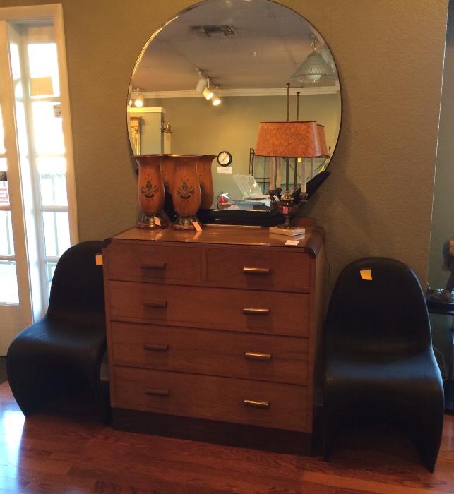 Art Deco dresser and mirror with black plastic chairs.